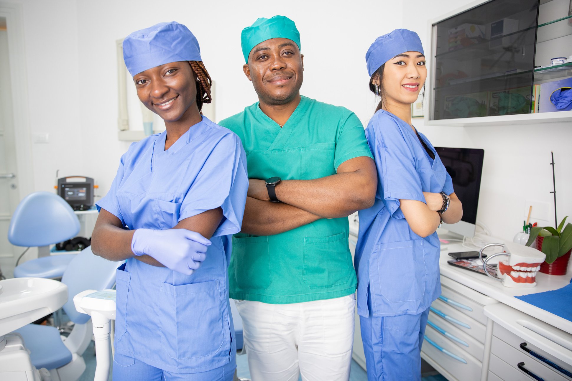 Three dentists pose smiling in a dental office, work in the health sector